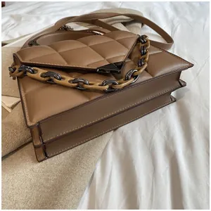 Close-up of quilted shoulder bag with resin chain and metal triangle closure