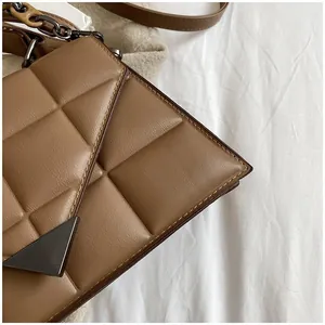 Close-up of brown quilted leather handbag with distinctive black triangular metal clasp