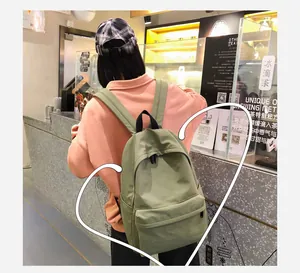 Vista trasera detallada de una mochila minimalista verde hierba en una cafetería