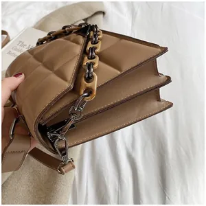 Detail view of brown quilted handbag with three-layer accordion structure and dual straps