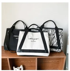 Trois sacs cabas en toile en noir, blanc et imprimé zèbre exposés sur une étagère en bois