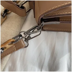 Close-up of brown quilted handbag with metal hardware and amber acrylic chain detail