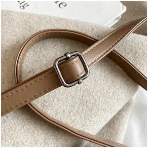 Macro detail of brown leather strap with silver square buckle on textured fabric