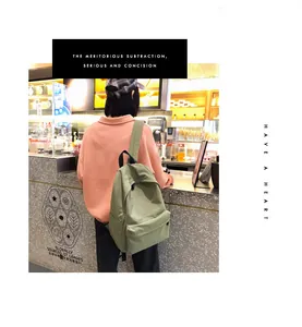 Vista posterior de la mochila minimalista de lona verde frijol en un entorno de café informal
