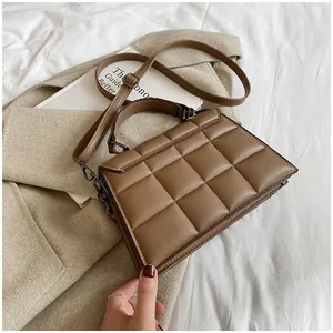 Brown quilted crossbody bag with adjustable strap over a beige wool coat detail view