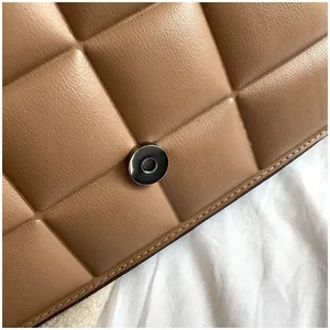 Macro detail of padded quilted khaki leather bag with silver magnetic snap closure