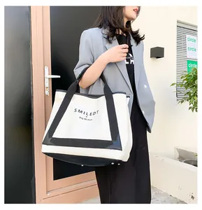 Détail du sac cabas en toile montrant les pieds en métal et les anses noires
