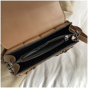 Interior view of brown faux leather square bag showing three spacious storage compartments
