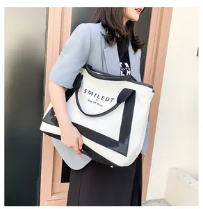 Détail du grand sac cabas en toile avec bordure en similicuir noir et texte de la marque