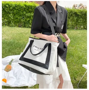 Sac fourre-tout en toile avec bordure noire et texte SMILED dans un décor extérieur