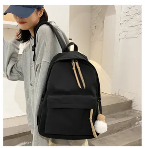 Close-up of black nylon backpack with decorative plush pendant and leather zipper pulls