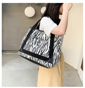 Vue latérale du grand sac cabas en toile zébré porté par un mannequin, design spacieux