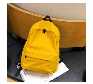 Vista detallada de la mochila minimalista amarilla con correas negras sobre madera