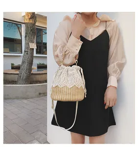 Detailed macro view of delicate white lace patterns on a straw bucket bag with gold chain