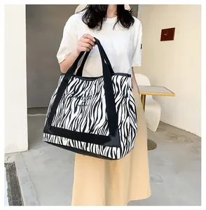 Détail du cabas en toile zébrée avec renforts en cuir noir et larges poignées robustes