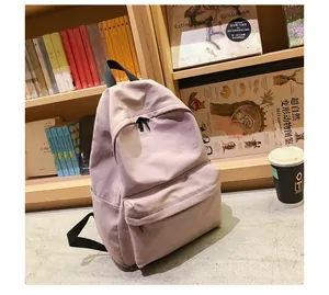Vista detallada de la mochila escolar de nailon rosa con bolsillos laterales en un escritorio