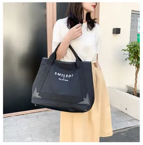 Grand sac cabas en toile noire pour femme avec lettrage blanc porté par un mannequin chic