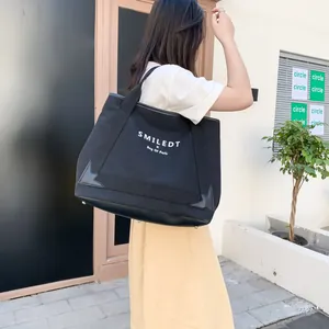 Détail d'un grand sac cabas en toile noire avec pieds en métal porté par un mannequin