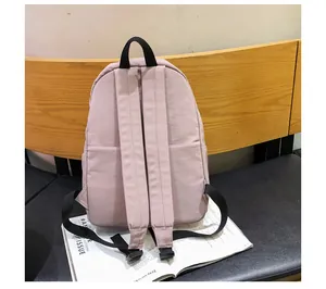 Detalle de una mochila de nailon rosa con correas acolchadas y bolsillos laterales en banco