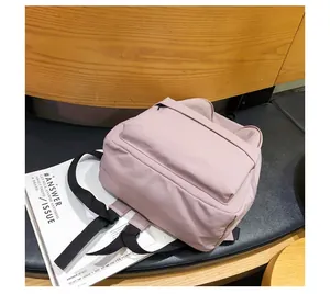 Detalle de mochila rosa con orejas de gato y correas sobre un asiento de cuero
