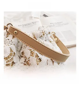 Detail of white lace floral straw bucket bag with faux leather handle and gold hardware