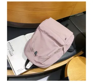 Detalle de una mochila de nylon rosa palo con correas negras sobre un banco
