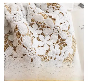 Macro detail of intricate white floral lace trim on a woven straw summer bucket bag