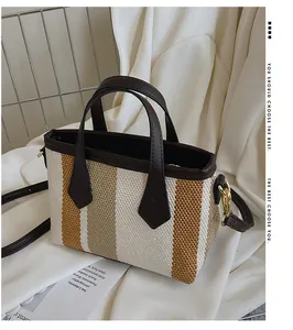 Detalle de un bolso cubo de lona tejida con rayas marrones y beige y herrajes oro