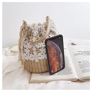 Detail of hand-woven straw bucket bag with white lace floral accents and leather strap