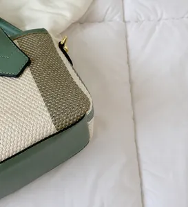Close-up of contrast stitching and gold metal buckles on a canvas bucket bag