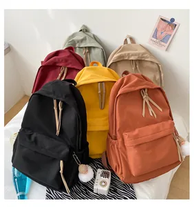 Minimalist nylon school backpack in multiple colors with front pocket and plush pendant
