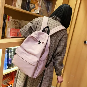 Mochila escolar rosa minimalista con correas acolchadas en entorno de biblioteca