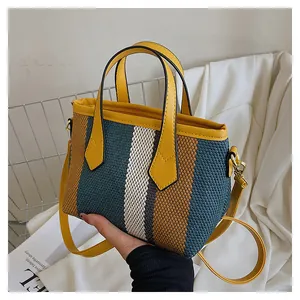 Detalle de bolso tejido multicolor con asas de cuero amarillo y herrajes dorados