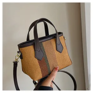 Detalle del mini bolso de paja tejido con diseño de rayas y asa de cuero marrón