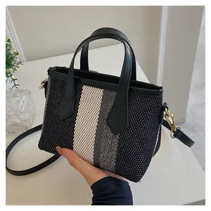 Detalle del bolso tote tejido tricolor con asas de cuero y correa de hombro extraíble