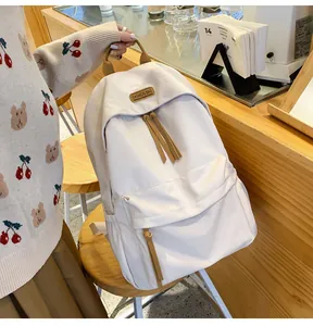 Detail of cream nylon backpack with khaki straps and fashion brand tag in a cafe setting