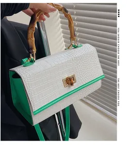 Détail de la poignée en bambou et du fermoir doré sur le sac à main en crocodile