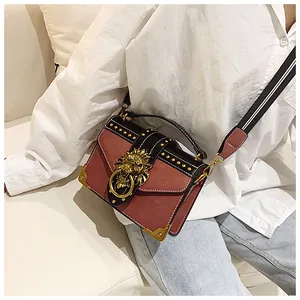 Detail of red and black leather handbag featuring golden lion head buckle and rivet accents