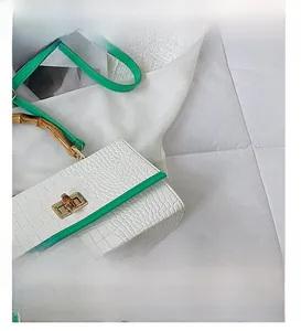 Vue détaillée de la poignée en bambou et du fermoir en métal sur sac blanc façon croco