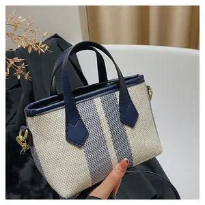 Detalle de un bolso cubo de lona con ribetes de cuero azul marino y herrajes dorados
