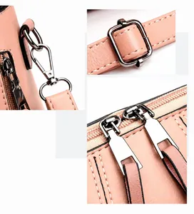 Detail view of silver zipper, metal hooks and adjustable strap on pink leather handbag