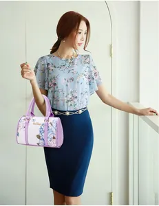 Detail of purple Boston handbag with blue floral print and gold logo accent