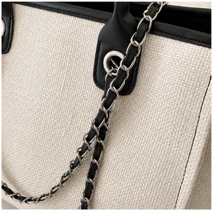 Detalle del tejido trenzado con ribete de cuero negro y cadena de metal plateado en el bolso