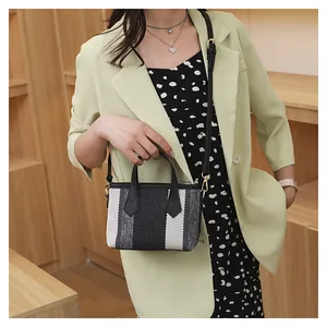 Detalle del bolso de lona tejida con rayas tricolores y asas de cuero negro