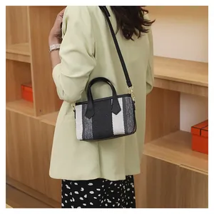 Detalle de mini bolso bombonera de tejido a rayas con chaqueta verde y vestido largo