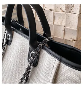 Detail der weißen Canvas-Beuteltasche mit schwarzem Lederbesatz und silberner Metallkette