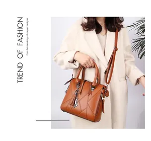 Brown faux leather tote bag featuring elegant tassel charm and decorative geometric stitching