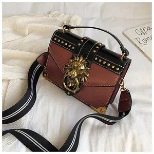 Detail of vintage rivets and golden lion head ornament on brown leather handbag