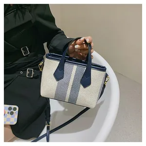 Detalle de bolso saco de lona a rayas azules y blancas con correa de cuero ajustable