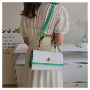 Détail du sac à main motif crocodile avec poignée en bambou et bords verts sur mannequin